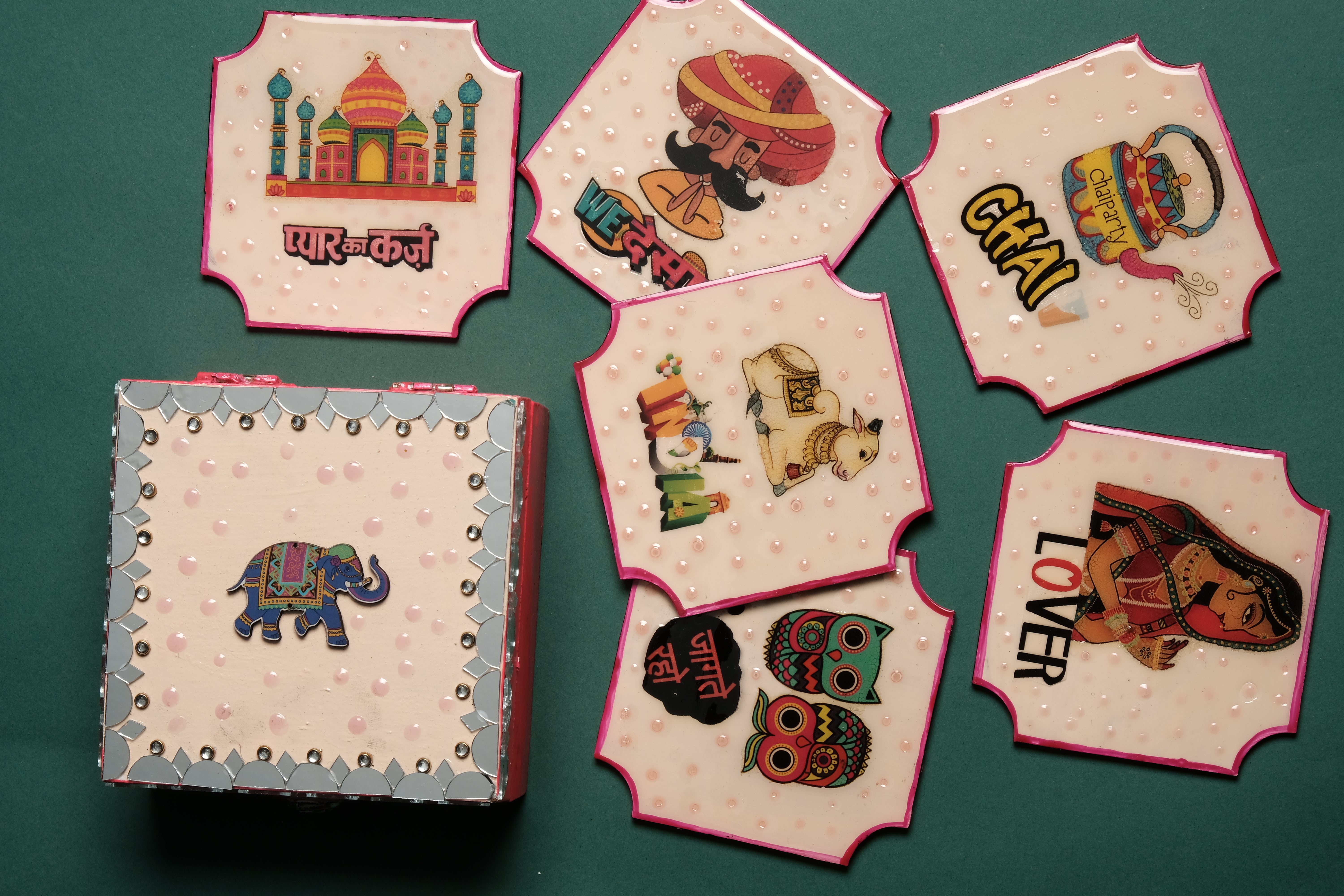 Decorative tea coaster set showing 6 hand-painted desi designs including Taj Mahal chai cups elephants and owls with wooden storage box with mirror work embellishment