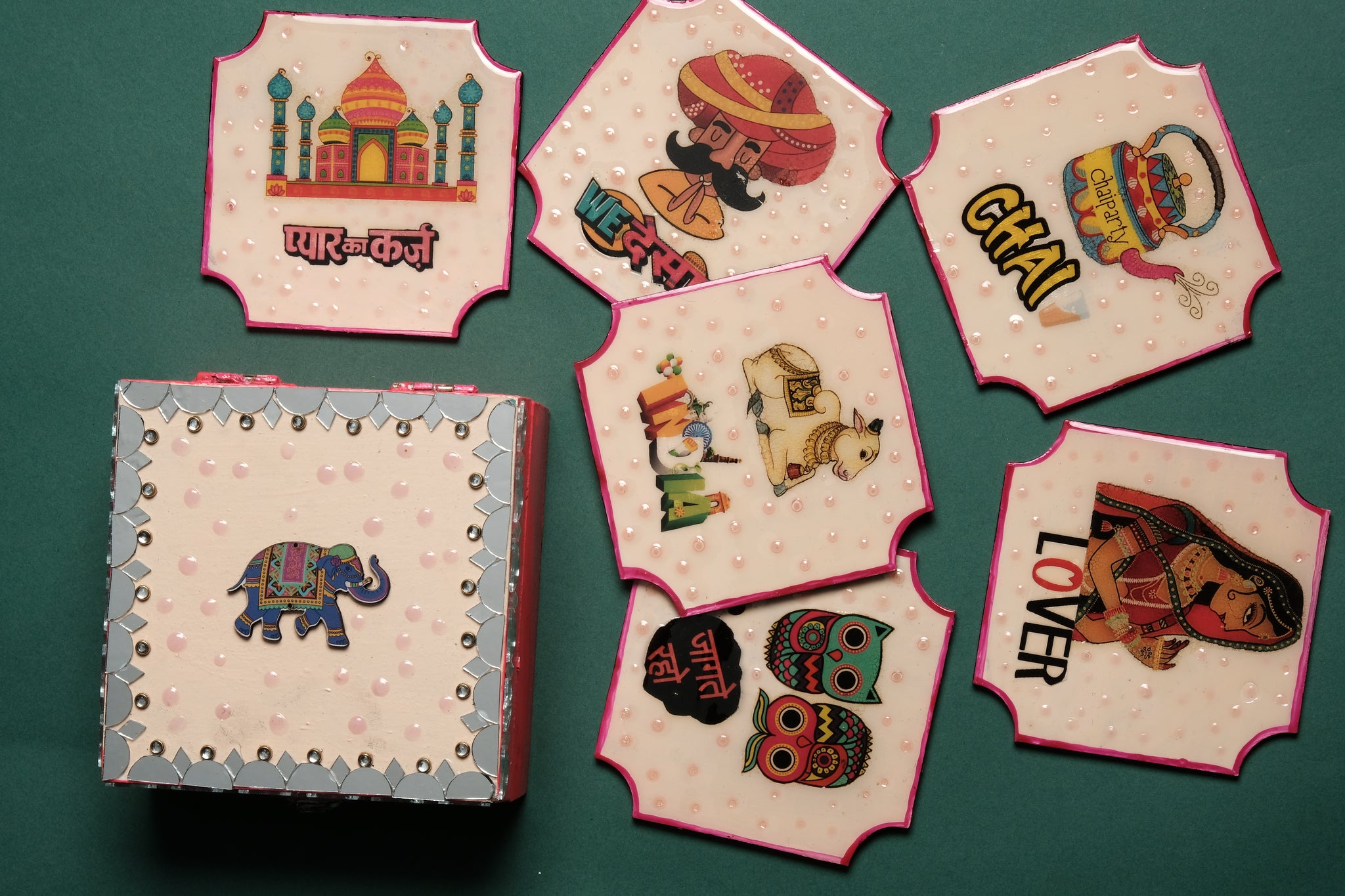 Decorative tea coaster set showing 6 hand-painted desi designs including Taj Mahal chai cups elephants and owls with wooden storage box with mirror work embellishment