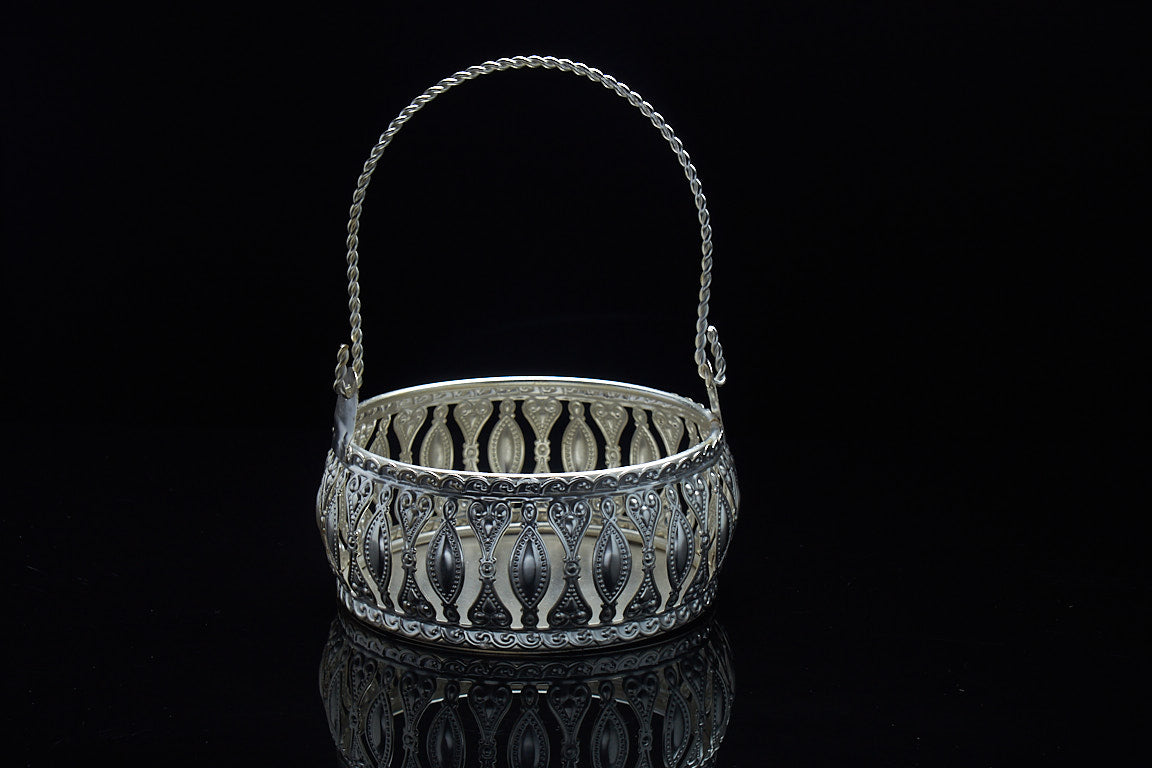 Decorative metal basket with extended twisted handle for Diwali return gifts showing versatile display and carrying functionality