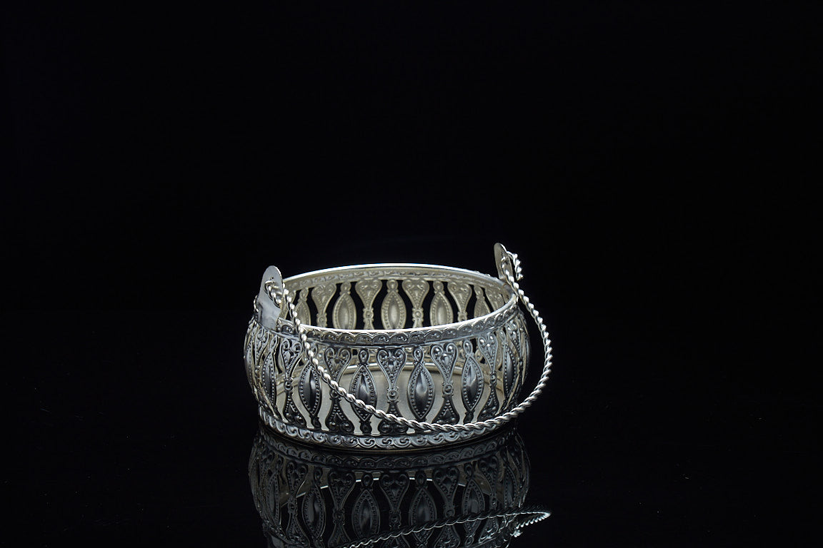 Close up detail of silver finish basket showing intricate filigree cutwork pattern and foldable handle for Diwali favor gifts