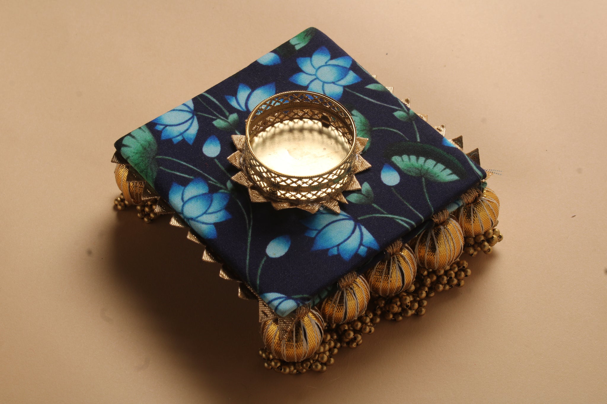 Textile diya favor with gota embellishment showing blue floral fabric pattern and gold metallic trim tea light holder