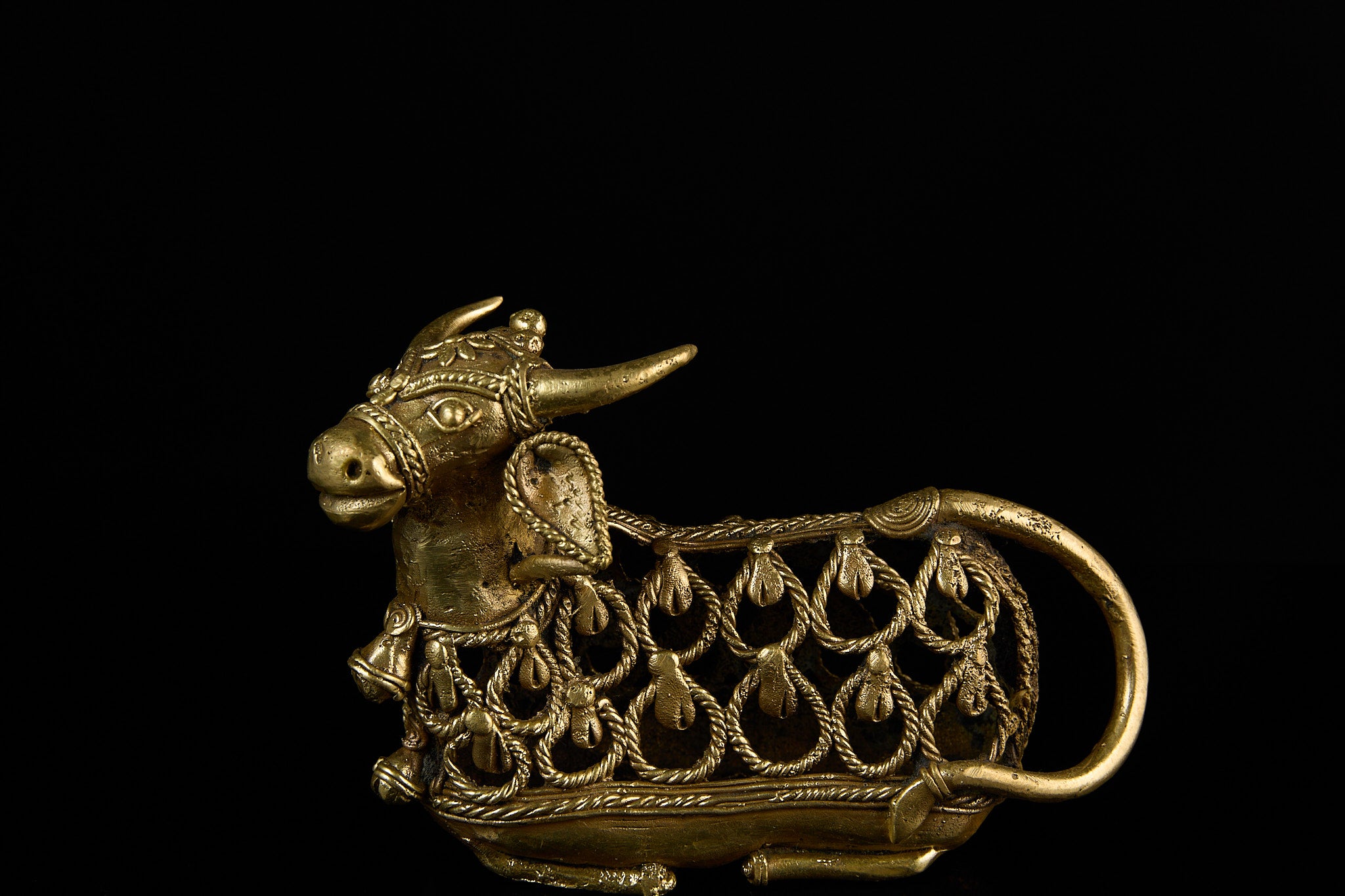 Angled three-quarter view of the brass Nandi Bull figurine, highlighting the detailed craftsmanship on its face and decorative neck bells.