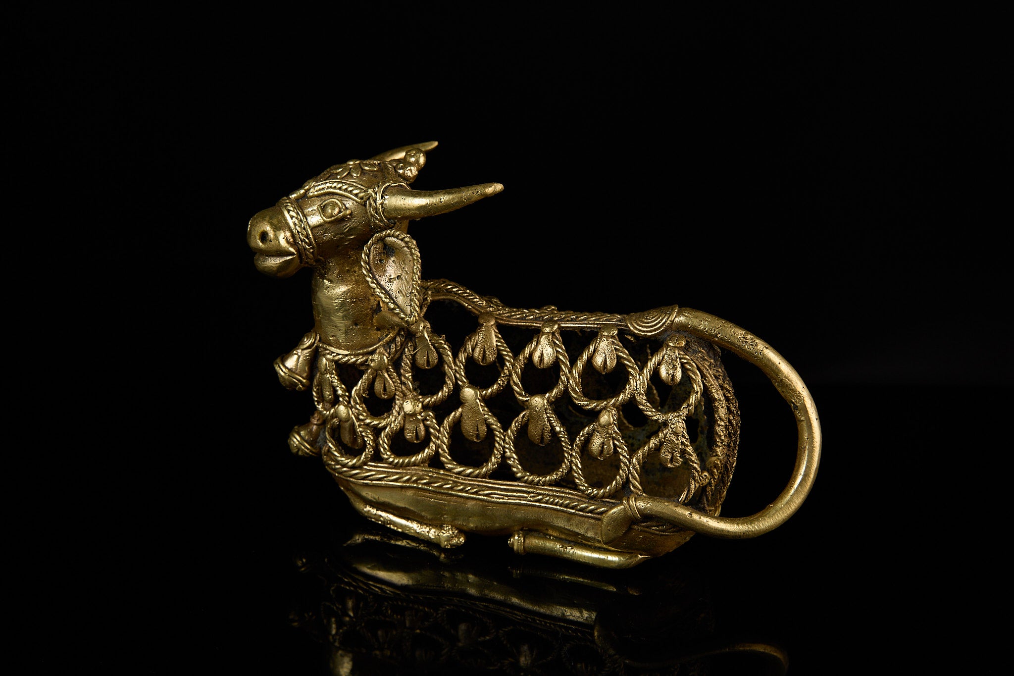 The brass Nandi Bull statue angled slightly toward the viewer, showing the depth and three-dimensional quality of the metal latticework.
