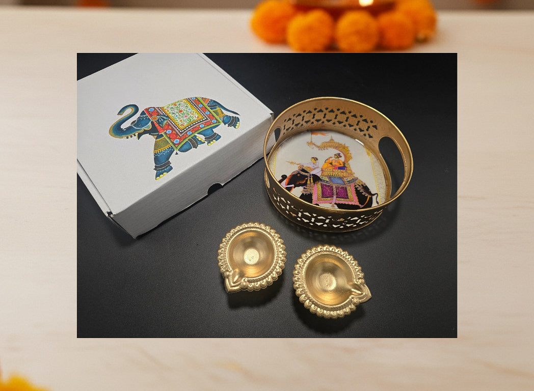 Diwali favor gift tray with 2 gold leaf diyas displayed with elephant print decorative gift box on dark surface