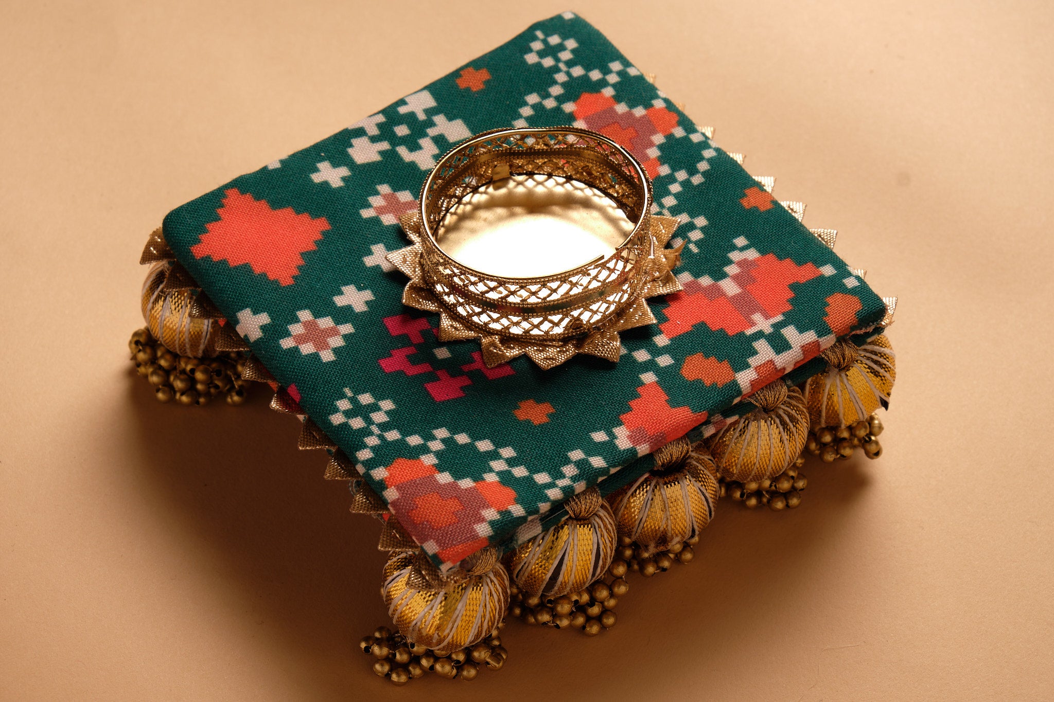 Handcrafted textile diya in green and coral geometric pattern with gold gota trim and decorative tassels