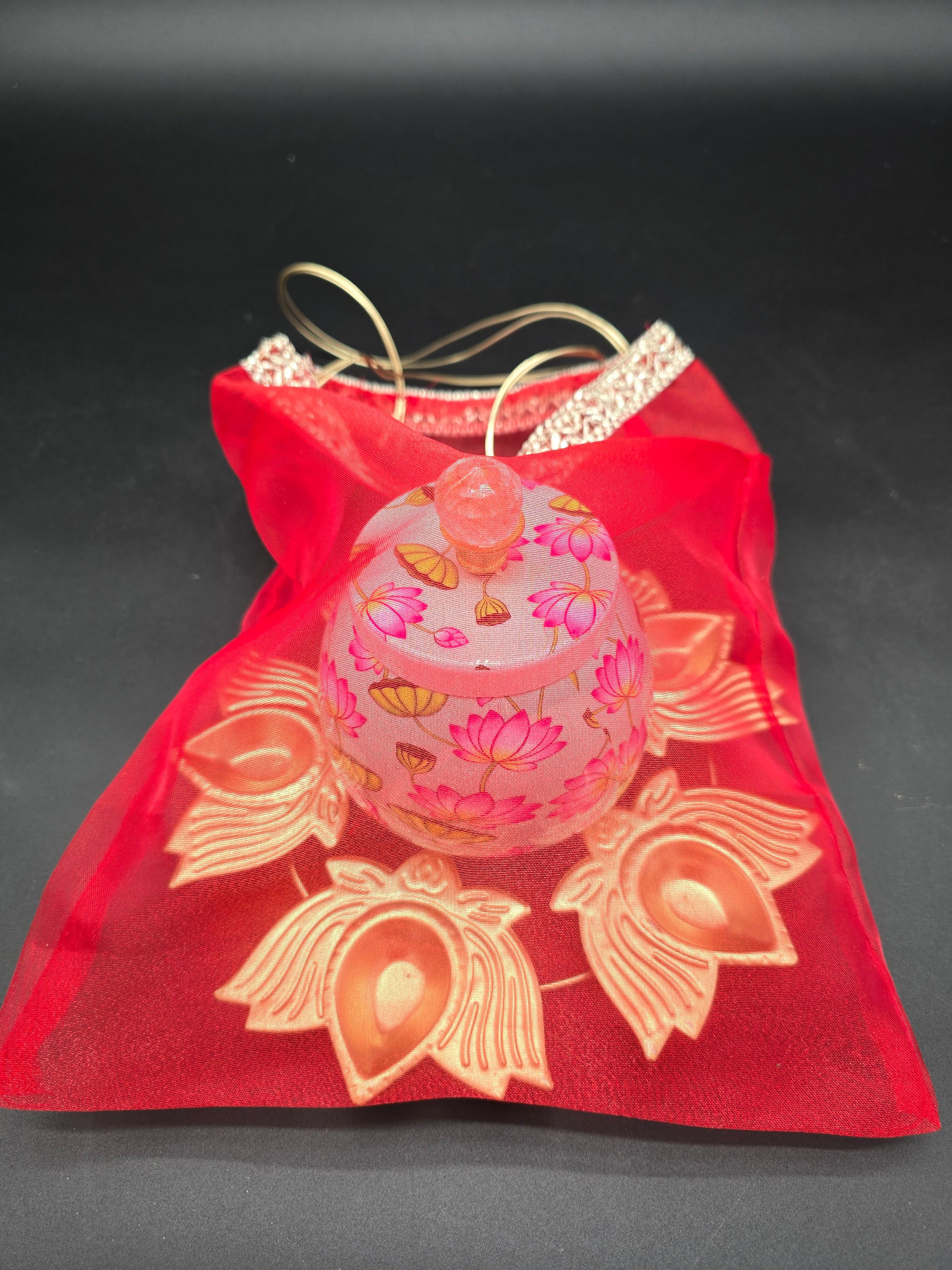 Diwali favor gift set showing decorative floral storage jar in red organza drawstring bag ready to give