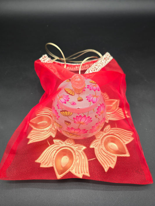 Diwali favor gift set showing decorative floral storage jar in red organza drawstring bag ready to give