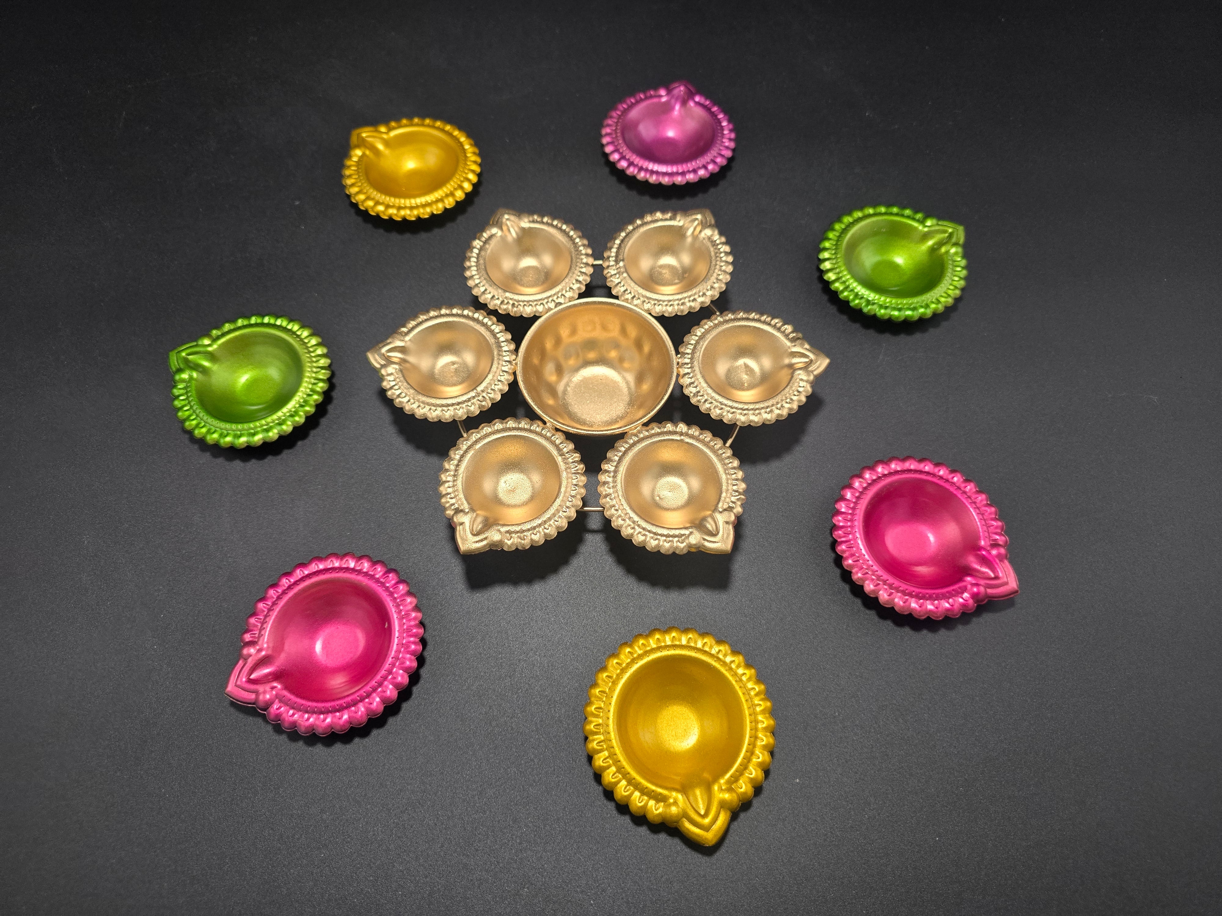 8 piece colorful Diwali diya set arranged in traditional rangoli pattern with gold center urli surrounded by bright colored diyas