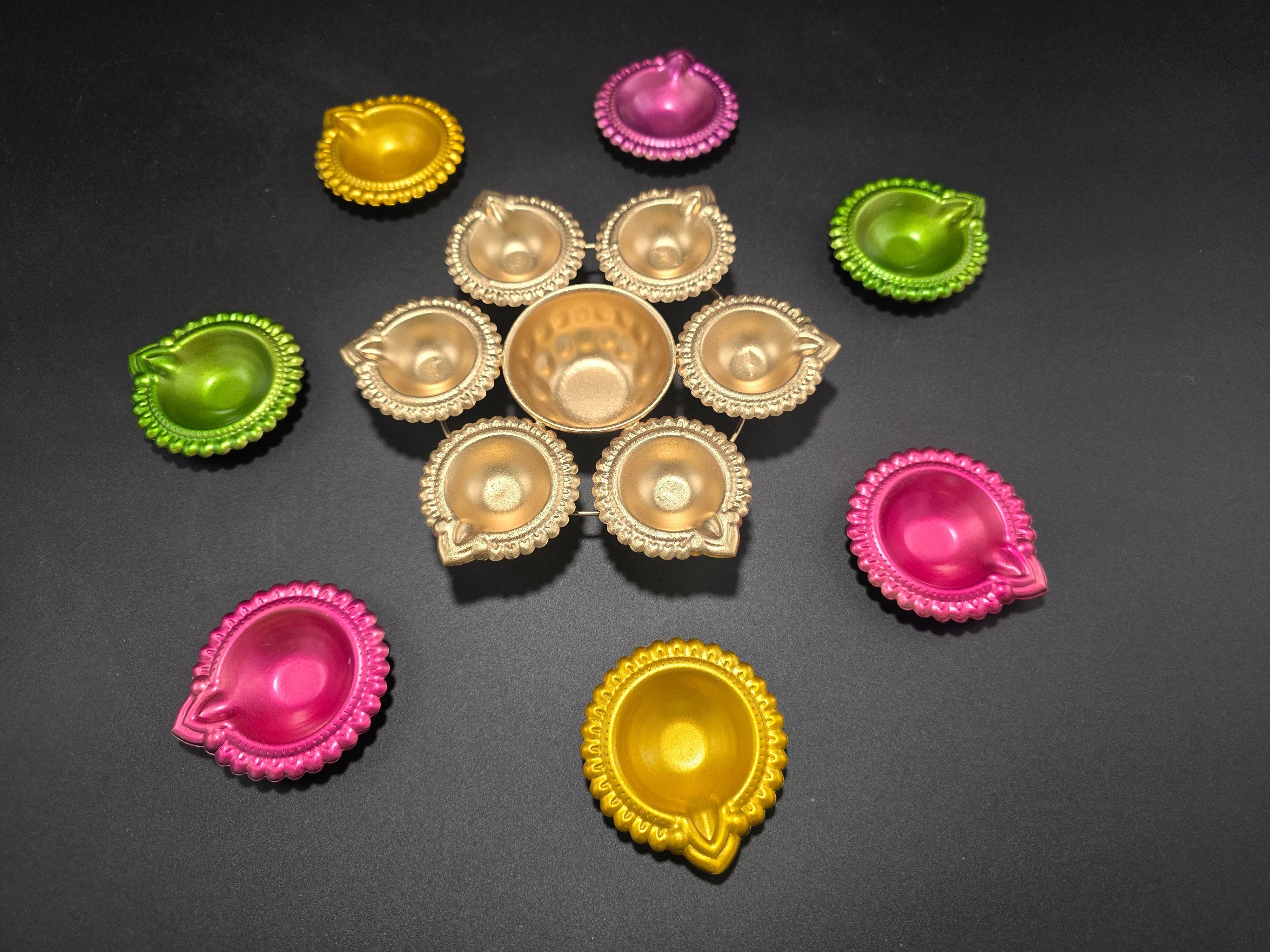 Colorful Diwali diya set showing 8 pieces including gold center urli and vibrant pink yellow green small diyas in iron with enamel finish