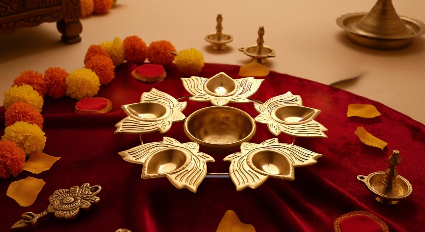 Traditional rangoli urli diya displayed on red fabric with marigold flowers and brass diyas showing Diwali pooja styling